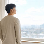 밝은 창밖을 바라보며 홀가분한 표정으로 서 있는 사람